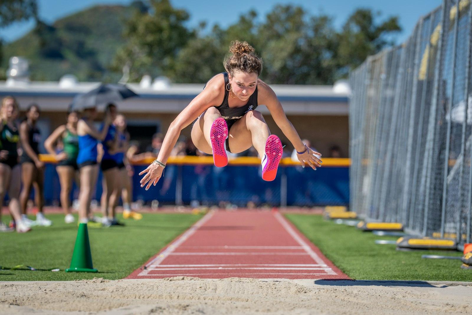 Long jumper in mid-flight above the sand pit