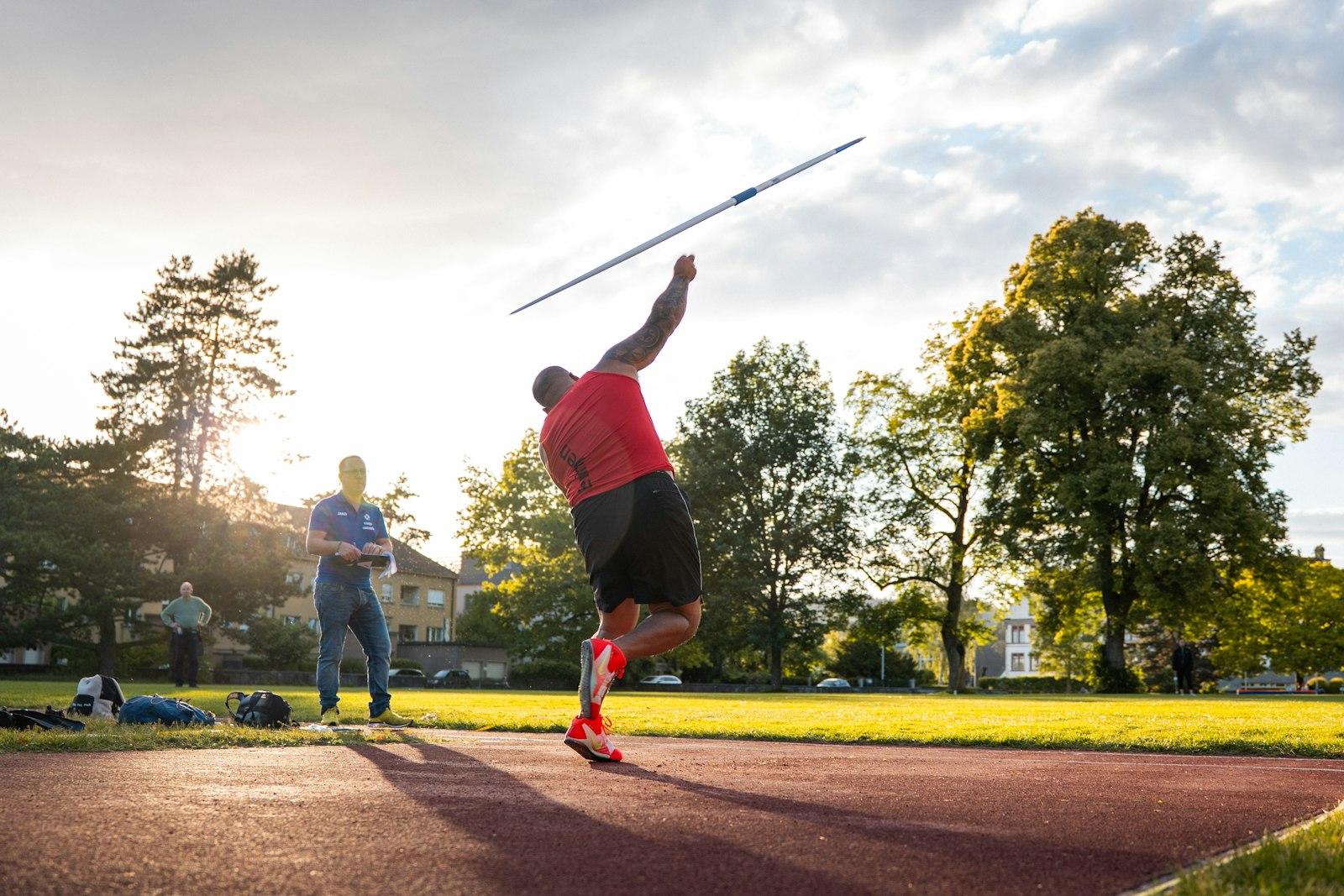 Athlete throwing a javelin on an athletics field at sunset